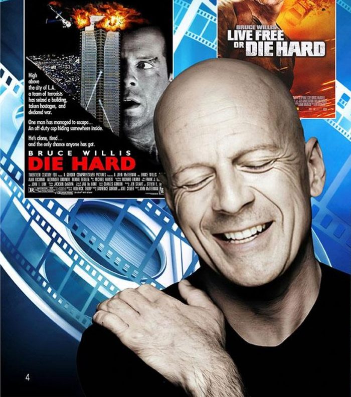 Bruce Willis smiling, with Die Hard and Live Free or Die Hard posters behind him